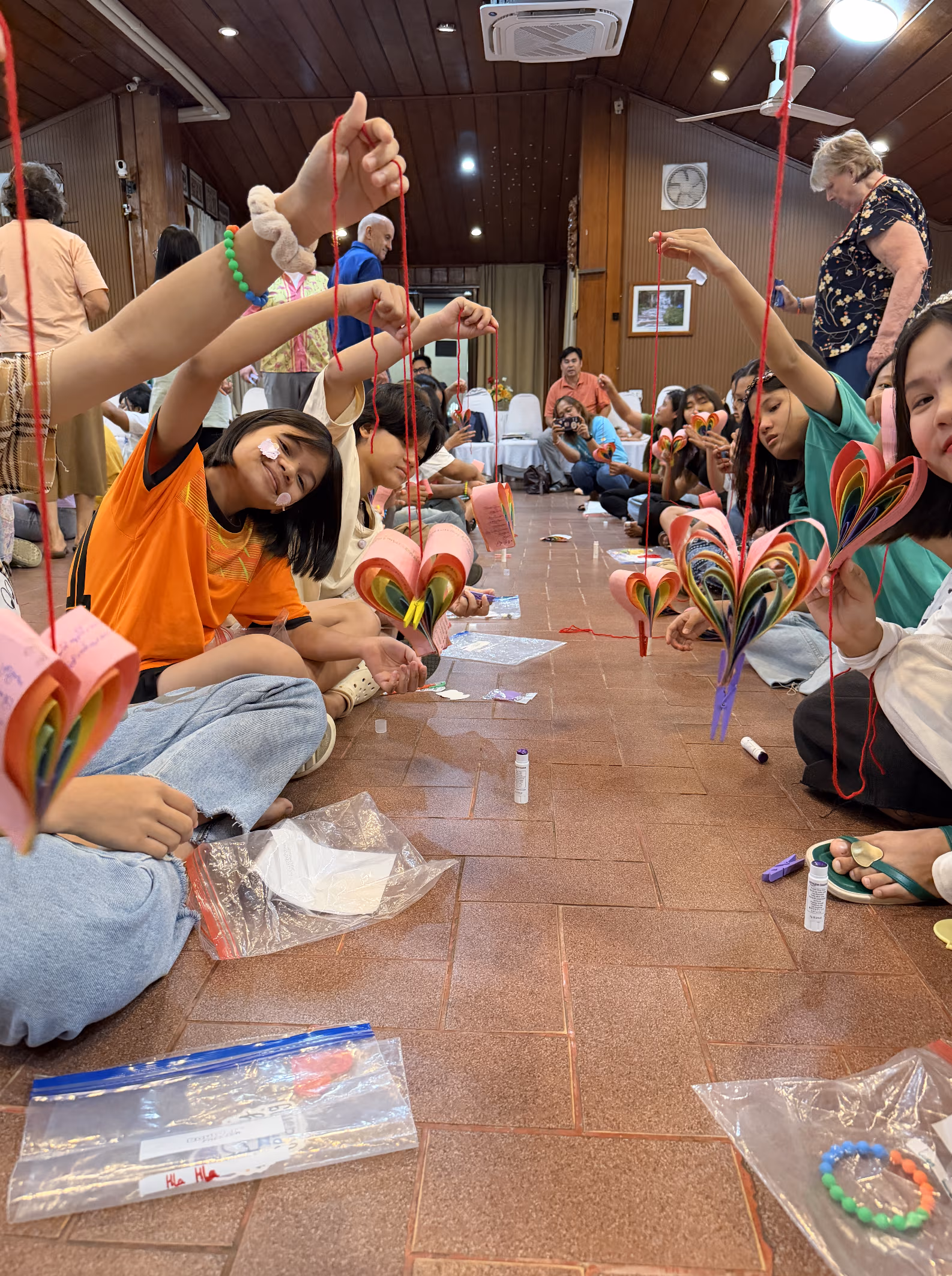 Girls proudly holding up their completed heart mobiles